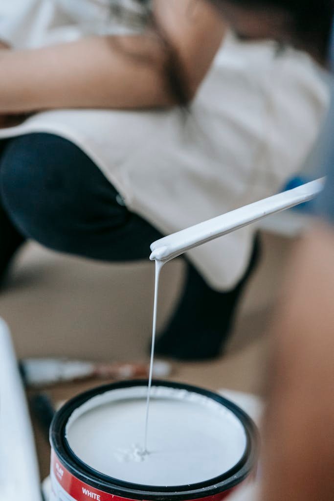 Close-up of a woman mixing white paint, ready to apply in a home renovation project.